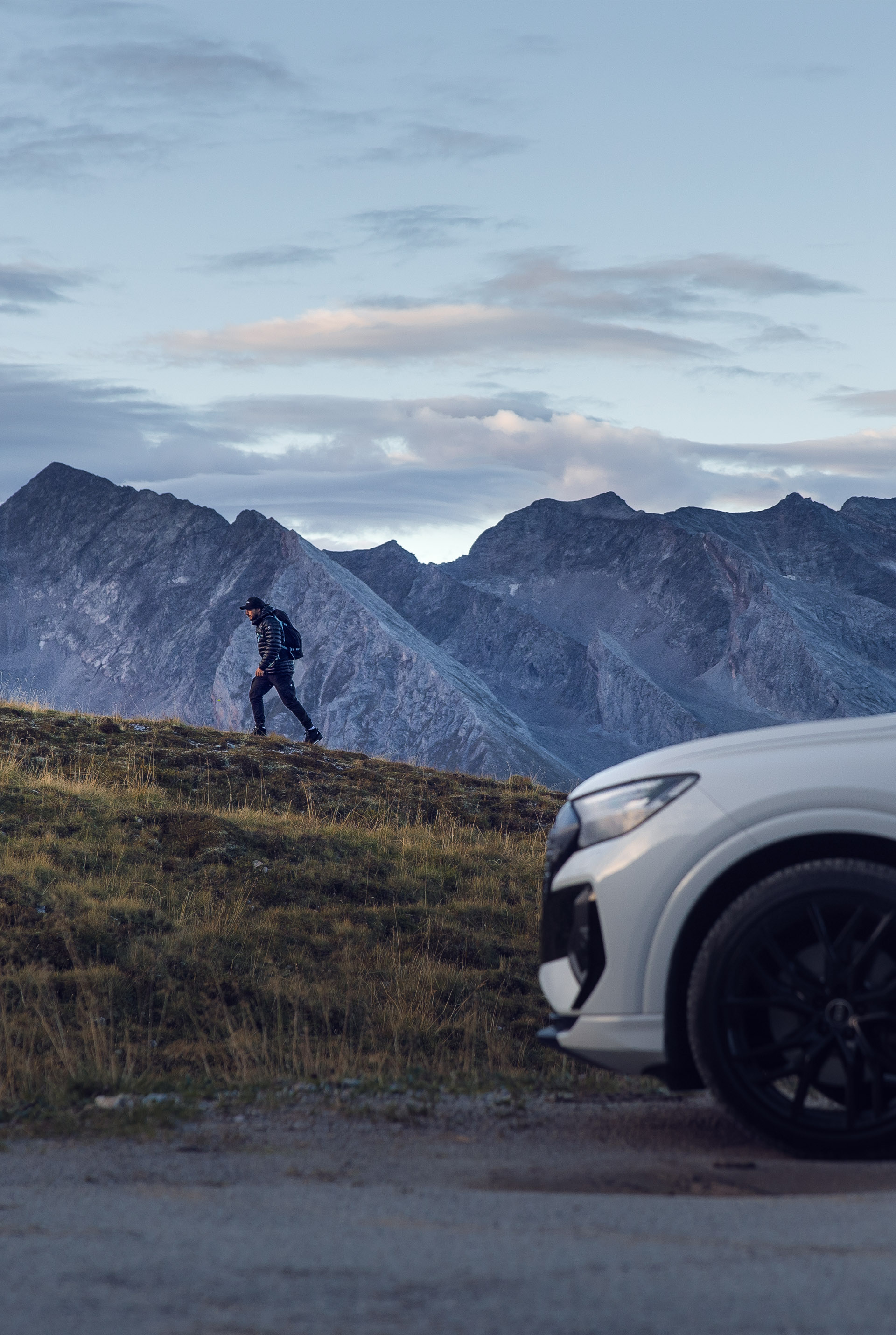 The white Audi Q4 e-tron stands in front of a mountain that Tom Klocker hikes up on foot.