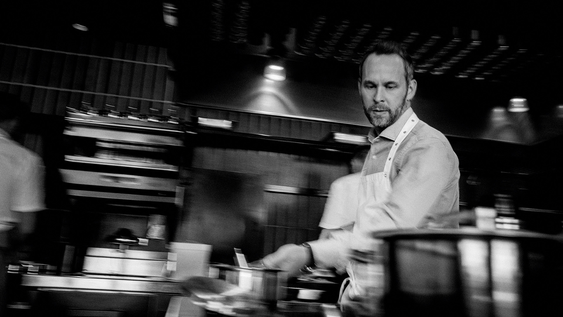 Svartvit bild som visar Björn Franzen framifrån som lagar mat.